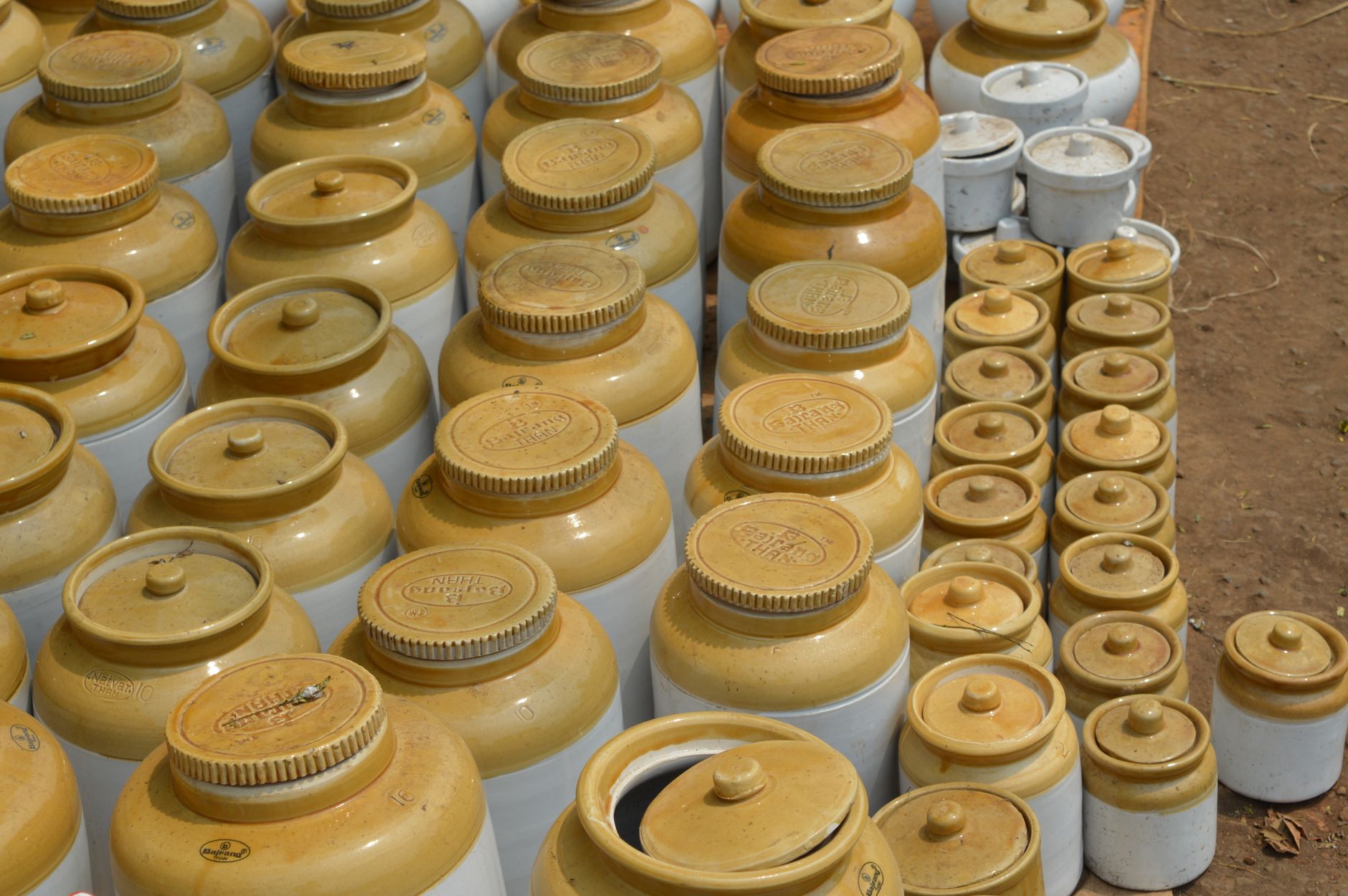 An arrangement of earthenware pots with lids in various sizes on display outdoors.